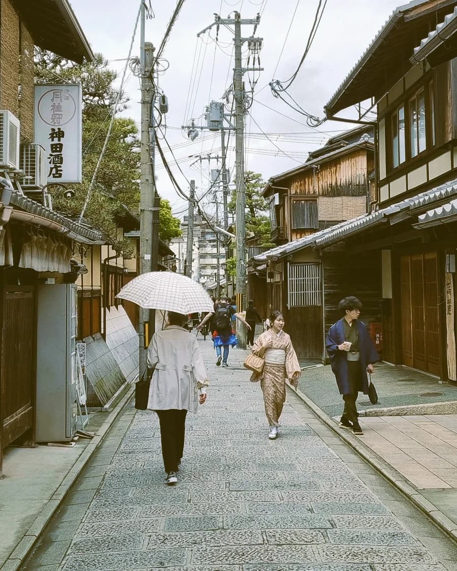 People walking under umbrellas on a traditional street in Kyoto, Japan